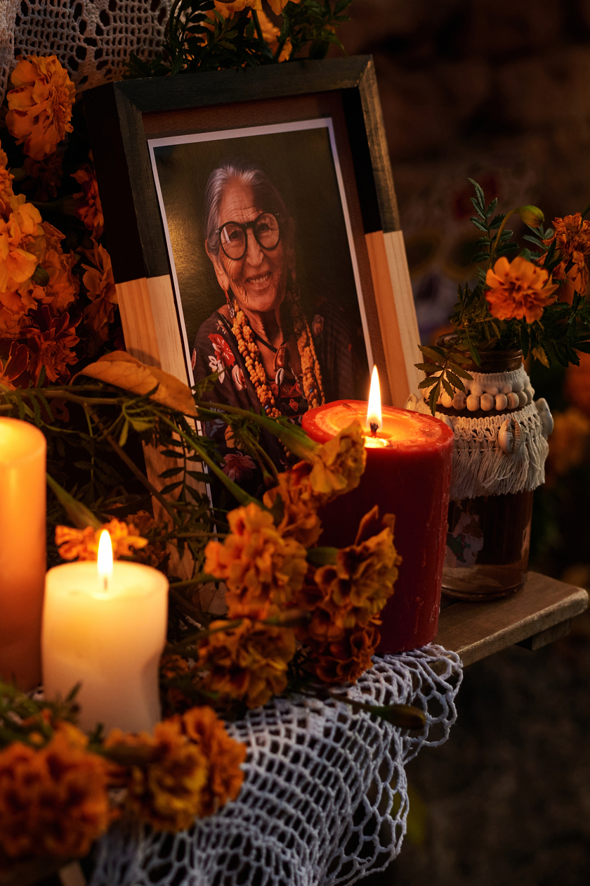 An ofrenda with a framed portrait, lit candles and marigolds.